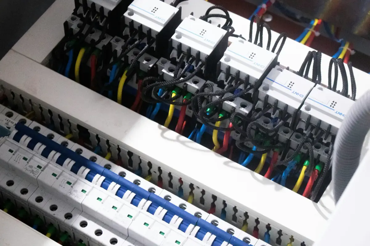 Rows of breakers and contactors inside an open electrical panel, with colour-coded conductors landed at the terminals
