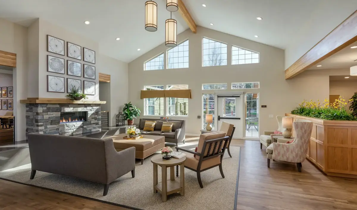 A vaulted common lounge with pendant lighting, recessed downlights and a lit stone fireplace