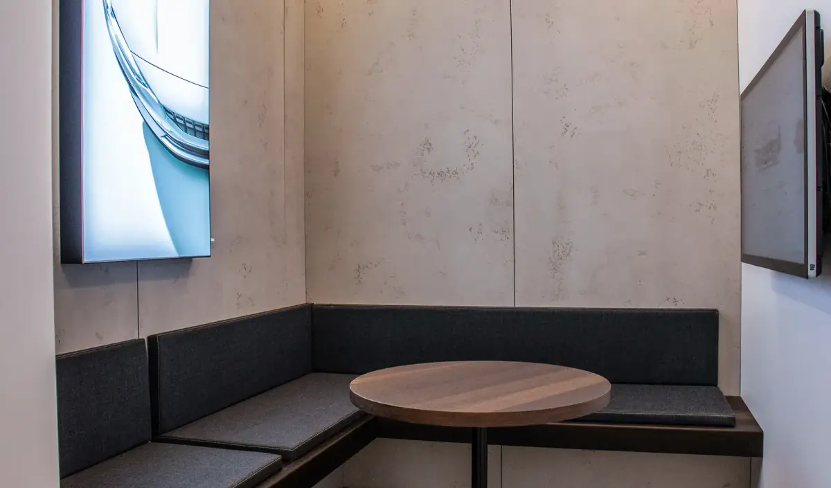 A seating nook in the showroom with banquette benches, a round table and a wall-mounted screen