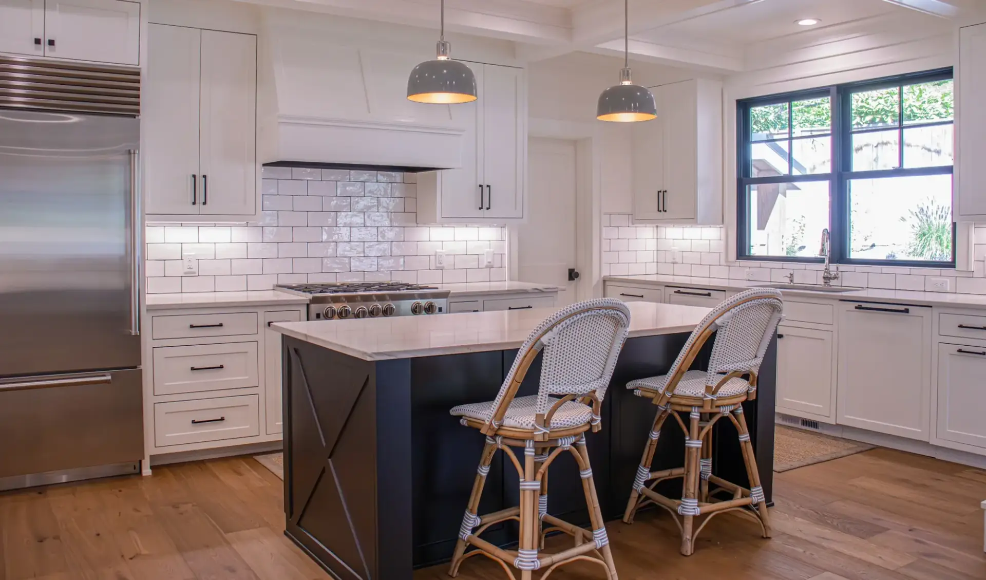 Rewired kitchen in a white-cabinet remodel — pendants over the island, under-cabinet lighting, recessed cans, and new receptacles along the backsplash