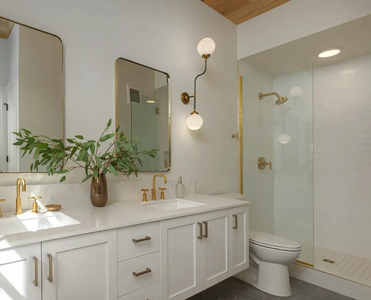 Finished bathroom lit by a brass globe sconce at the vanity and recessed fixtures over the shower