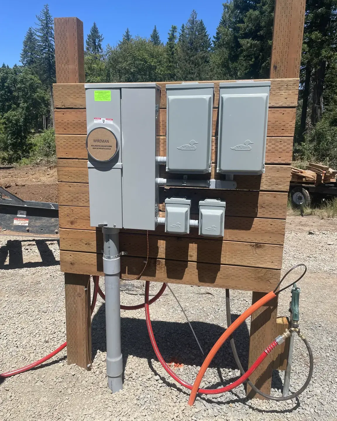 Temporary power pedestal on a cleared building lot, meter and disconnects mounted to a timber frame with the county permit tag still on it
